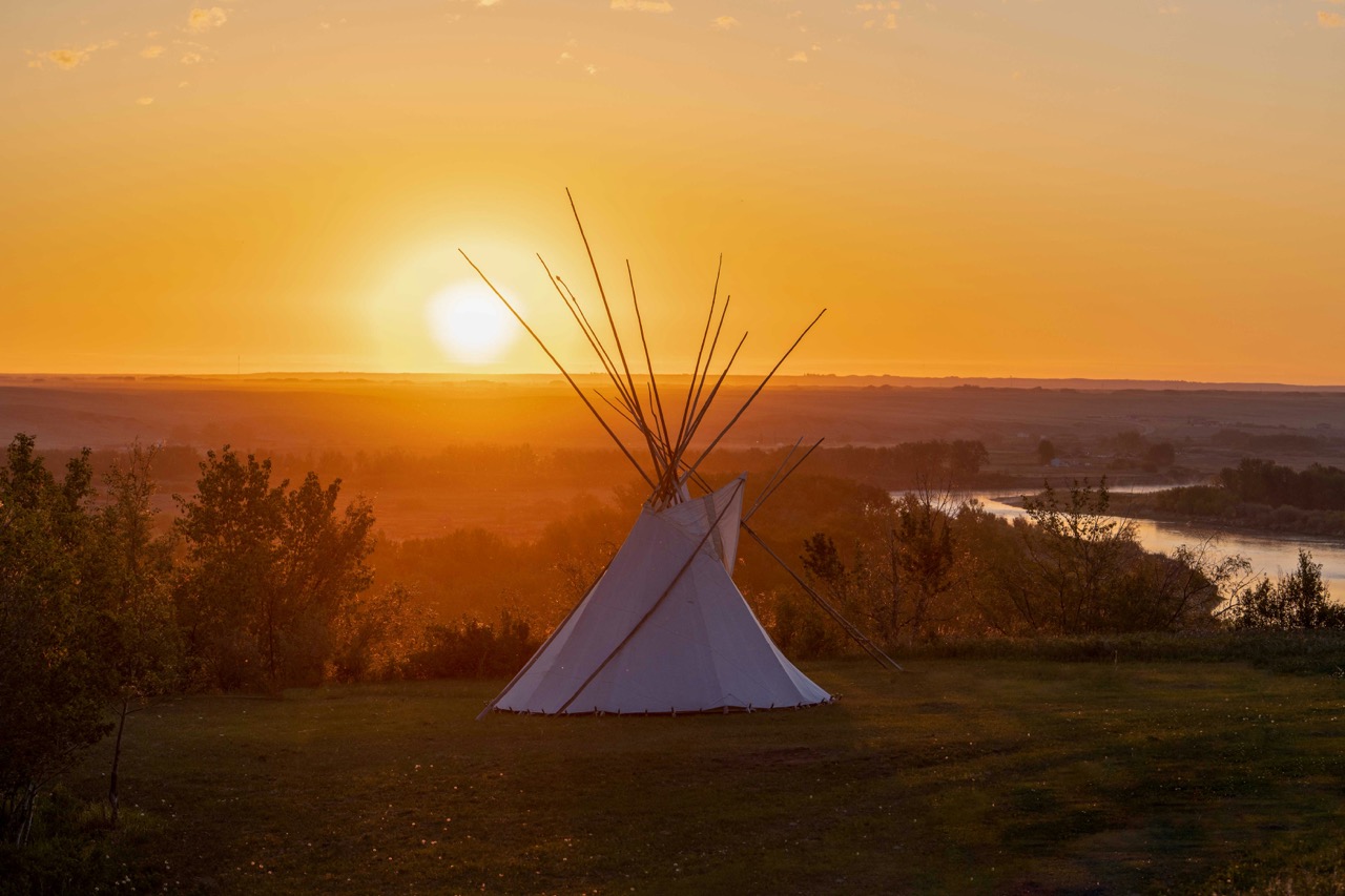 Tipi silhouetted against a glowing prairie sunset